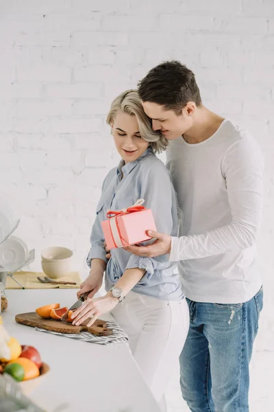 Freundin Schneidet Grapefruit Und Freund Schenkt Ihr Geschenkkarton Der Küche — Stockfoto