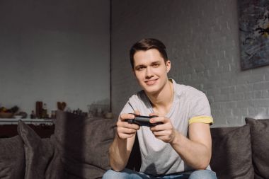 oyun çubuğu tutan ve kameraya bakarak gülümseyen yakışıklı adam 