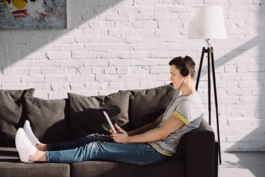 yakışıklı adam evde tablet ile müzik dinlemek yan görünüm