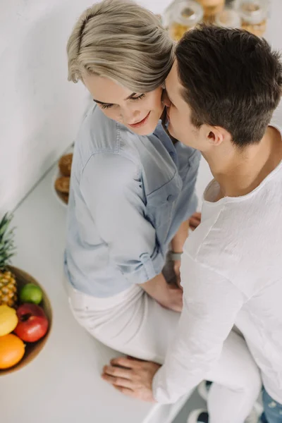 キッチン カウンターでガール フレンドのキスの彼氏のオーバー ヘッド ビュー — ストック写真