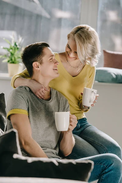 Sonriente Pareja Sosteniendo Tazas Café Mirándose Casa — Foto de Stock