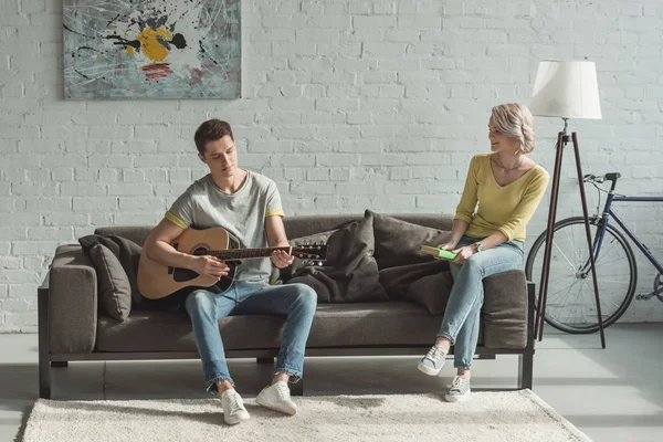 男友在家里为女朋友弹奏声学吉他 — 图库照片