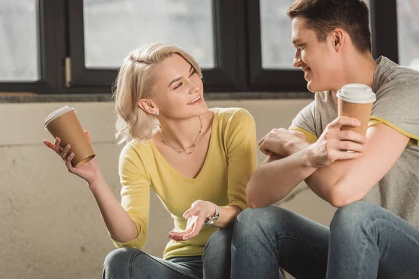 Sonriente Pareja Sentada Con Tazas Café Desechables Hablando Casa — Foto de Stock