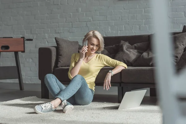 Menina Bonita Sentado Chão Falando Por Smartphone Olhando Para Laptop — Fotografia de Stock