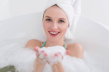 baş banyosunda rahatlatıcı spa salonda köpükle üzerinde havlu ile gülümseyen kadın