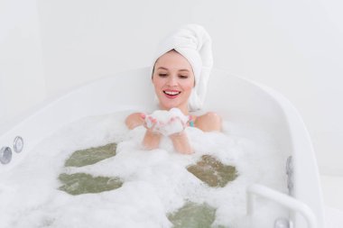 baş banyosunda rahatlatıcı spa salonda köpükle üzerinde havlu ile gülümseyen kadın