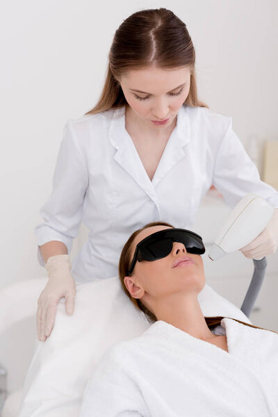 young woman getting laser hair removal procedure on face in salon