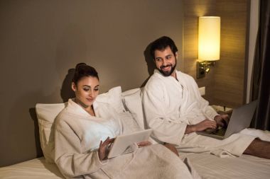 gülümseyen iki otel Süiti yatakta aygıtından bornoz içinde