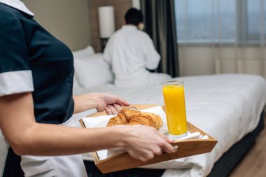 hizmetçi üniformalı kruvasan ve otel konuk için suyu tutan kırpılmış atış