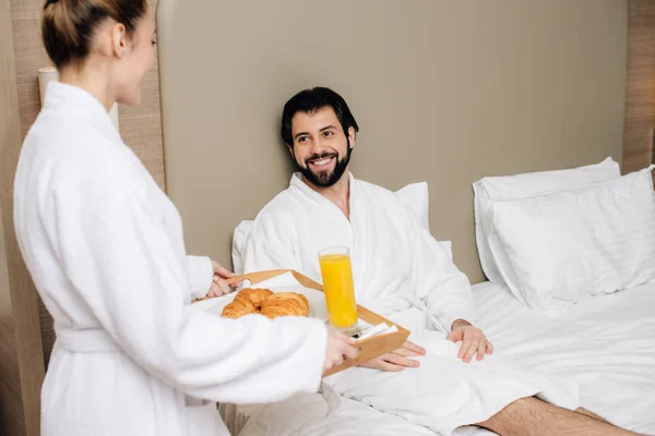 妇女携带托盘与早餐的男朋友在酒店套房 — 图库照片