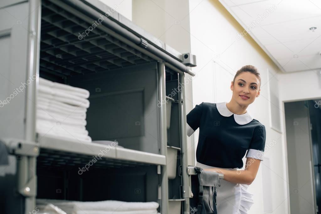 young beautiful maid in uniform driving housekeeping cart