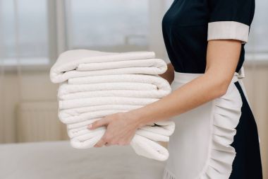 hizmetçi üniformalı otel odasında temiz havlu yığını tutan kırpılmış atış