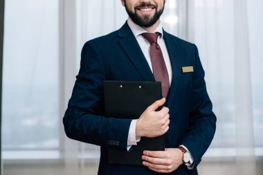 cropped shot of smiling hotel administrator with clipboard clipart