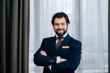 Kameraya bakarak çapraz kollu yakışıklı otel Yöneticisi