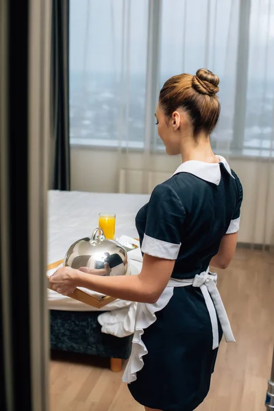 年轻有吸引力的女仆在制服举行早餐覆盖在托盘上索菲特克洛什 — 图库照片
