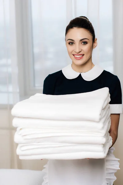 Junge Glückliche Dienstmädchen Uniform Halten Stapel Sauberer Handtücher Und Schauen — Stockfoto