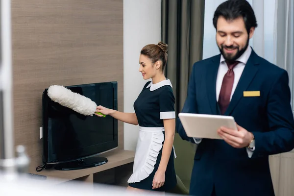 Ξενοδοχείο Διαχειριστή Χρησιμοποιώντας Tablet Στο Δωμάτιο Ενώ Υπηρέτρια Που Εργάζονται — Φωτογραφία Αρχείου