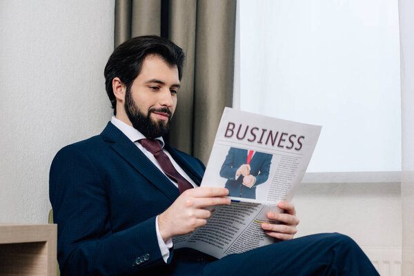 smiling handsome businessman reading newspaper at hotel room