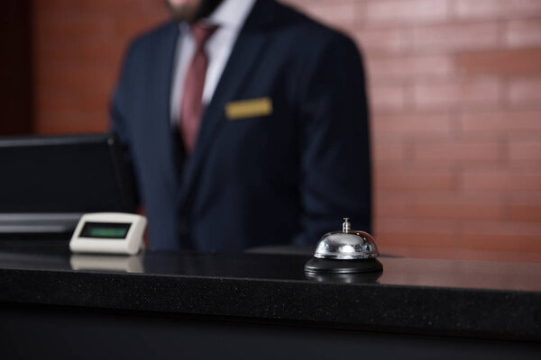 hotel reception desk with bell and blurred receptionist on background