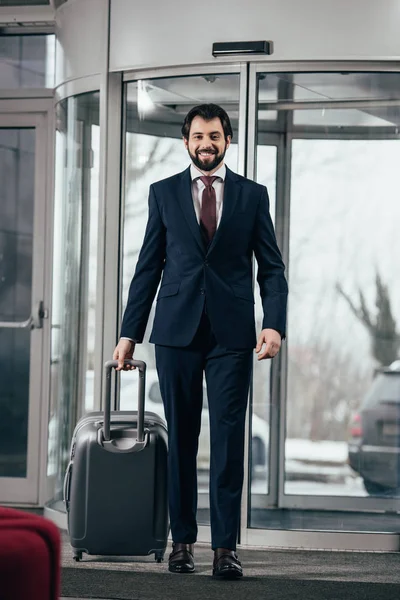 Glücklicher Gutaussehender Geschäftsmann Mit Gepäck Geht Aus Dem Hotel — kostenloses Stockfoto
