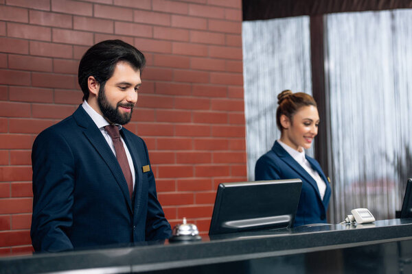 hotel receptionists working with computers together at counter