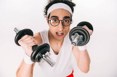 Portrait of young thin sportsman in eyeglasses holding dumbbells isolated on white clipart