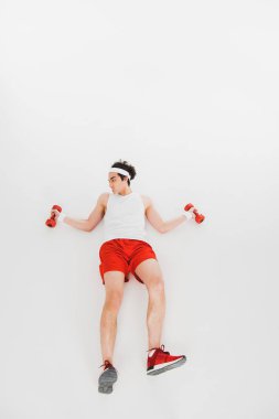 İnce sporcu üzerinde beyaz izole dumbbells ile yerde yatarken