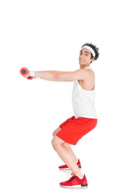 Beyaz izole dumbbells ile gülümseyen ince sporcu yan görünüm