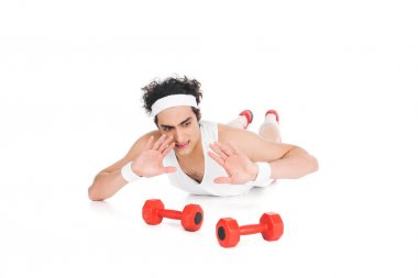 Young thin sportsman lying on floor and rejecting to exercise with dumbbells  clipart