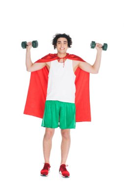 Smiling skinny sportsman with dumbbells standing in red cape isolated on white clipart