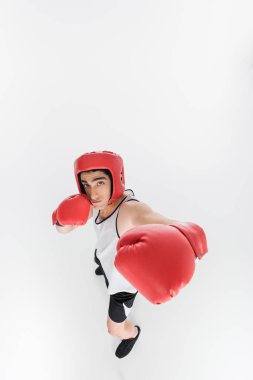 Boks eldivenleri ve kask üzerinde beyaz izole sıska sporcunun yüksek açılı görünüş