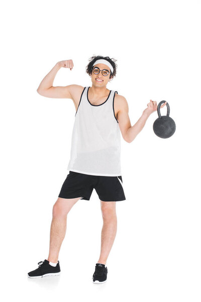 Молодой тощий спортсмен в очках держит гири и показывает мышцы, изолированные на белом
