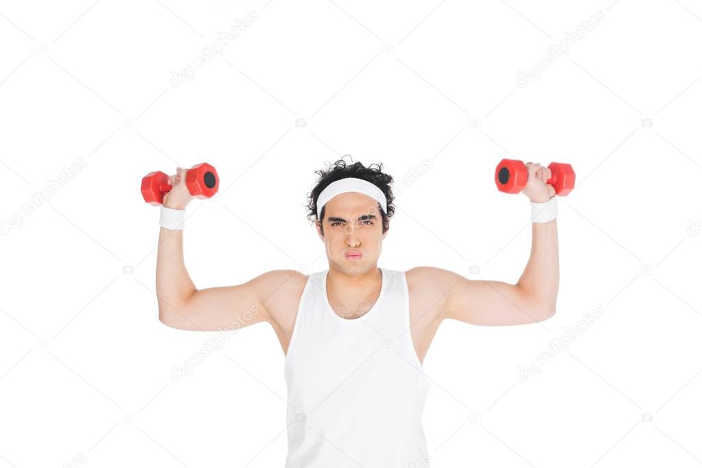 Young skinny man in headband exercising with dumbbells isolated on white