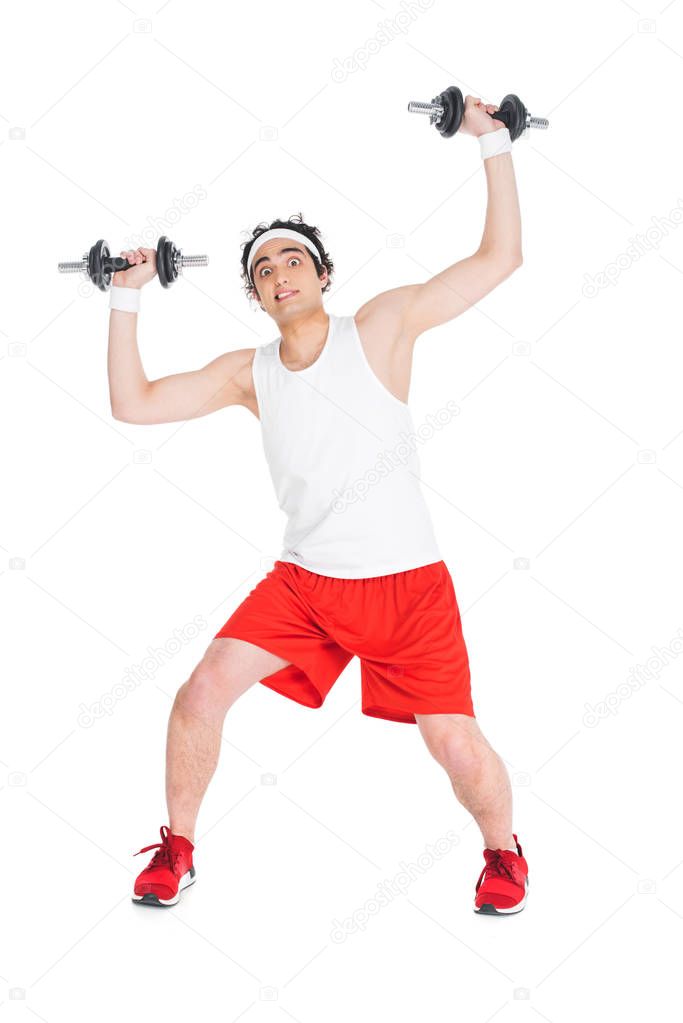 Young skinny man in sportswear holding dumbbells isolated on white