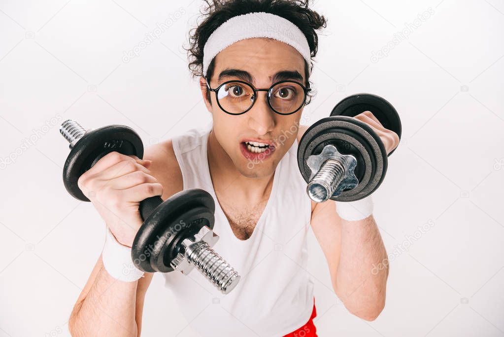 Portrait of young thin sportsman in eyeglasses holding dumbbells isolated on white