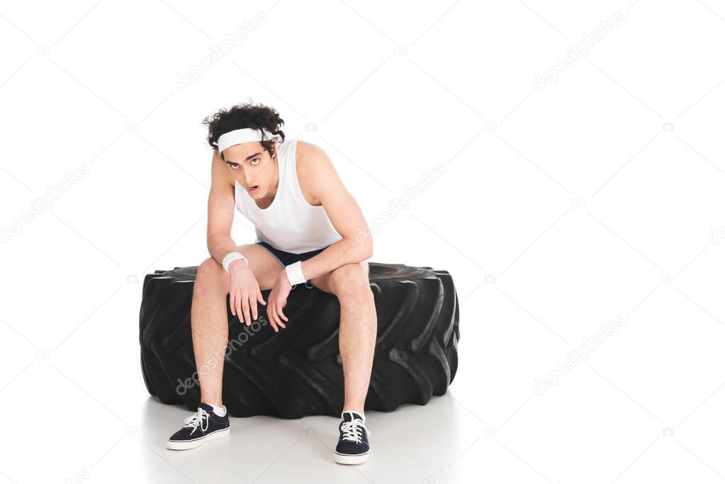 Tired thin sporstman sitting on tire of wheel isolated on white