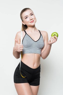 Elma tutarak ve üzerinde beyaz izole bant ölçme gülümseyen fitness kadın