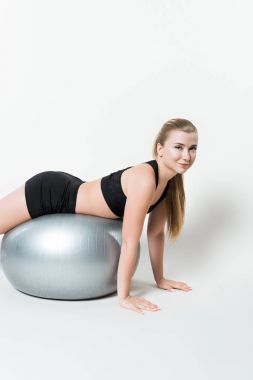 Attractive sportive woman on fitness ball isolated on white clipart