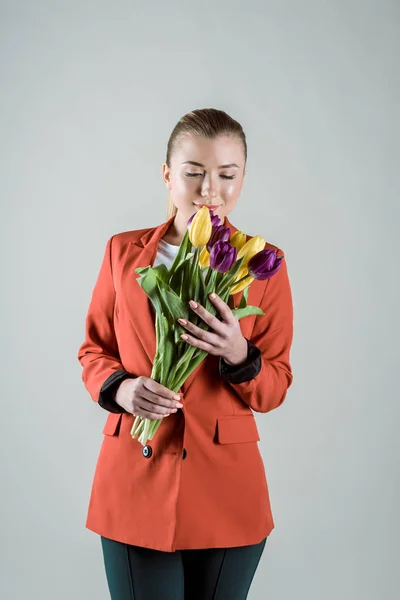 グレーに分離されたチューリップの花束を持った魅力的な女性  — 無料ストックフォト