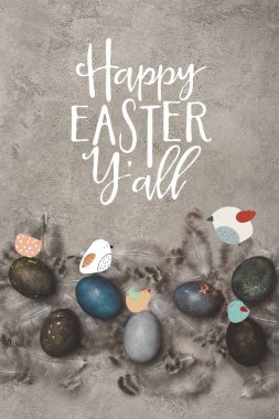 top view of painted easter eggs with feathers on concrete surface with birds and Happy Easter you all lettering