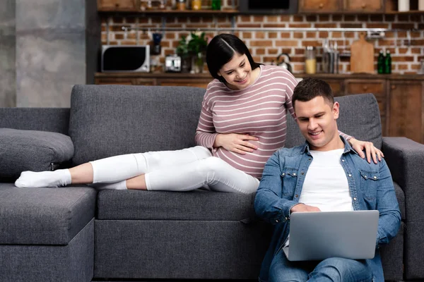 Gelukkige Jonge Zwangere Paar Laptop Thuis Gebruiken — Stockfoto