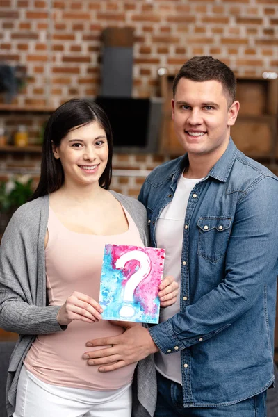 Happy Young Pregnant Couple Holding Card Question Mark Smiling Camera — Stock Photo, Image