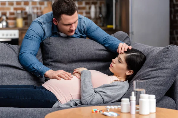 Junger Mann Berührt Auf Couch Liegende Kranke Schwangere Stirn Und — Stockfoto