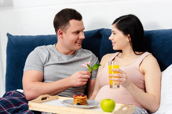 Feliz Joven Embarazada Pareja Desayunando Cama Hombre Presentando Flor Mujer — Foto de stock gratis