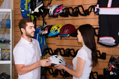 Bisiklet kask tutarak ve birbirine birlikte bisiklet dükkanında çalışırken bakarak genç yöneticileri yan görünüm