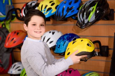 Bisiklet kask tutarak ve Bisiklet dükkanı kamerada gülümseyen sevimli küçük çocuk 