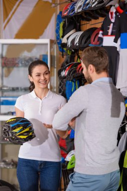 Bisiklet kask tutarak ve alıcı bike Shop bakarak gülümseyen kadın işçi