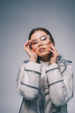 şık yağmurluk ve gri arka plan üzerinde kameraya bakarak gözlük güzel kadın portresi