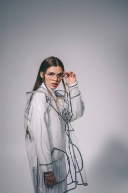 trendy yağmurluk ve gri arka plan üzerinde kameraya bakarak gözlük moda kadın portresi