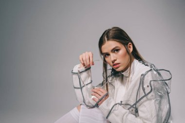 trendy yağmurluk kameraya gri arka plan üzerinde seyir gözlük ile şık kadın portresi